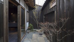 A traditional Japanese-style courtyard with a stone pathway, wooden fences, and a small garden area. - Sanjusangendo Yoitsubaki (Kyoto)