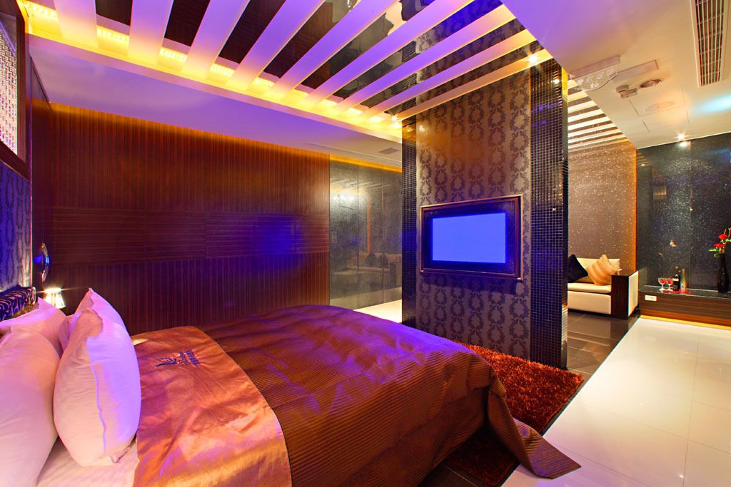 A modern hotel room with a large bed, a flat-screen TV, and a seating area with a sofa and a small table.