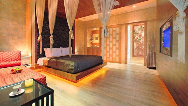 A spacious bedroom with a large bed, a bedside table, and a canopy bed. - Le Chateau Hotel (Zhushan)