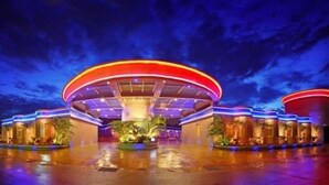 A modern hotel with a circular central atrium, surrounded by palm trees and illuminated by vibrant lights. - Le Chateau Hotel (Zhushan)