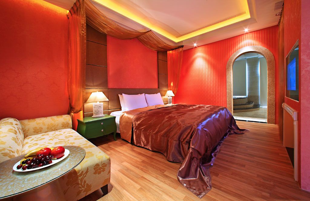 Quarto de hotel com uma cama grande, um sofá, uma mesa de cabeceira e uma cesta de frutas.