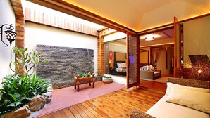A modern interior with a wooden floor, a stone wall, and a seating area with cushions. - Le Chateau Hotel (Zhushan)