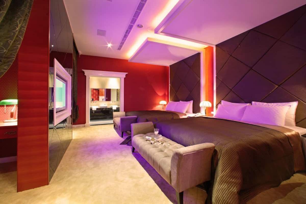 Une chambre d’hôtel moderne dotée d’un grand lit, d’un coin salon et d’une salle de bain visible à travers une porte ouverte.