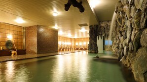 Una gran piscina interior con pared de piedra y una cascada.