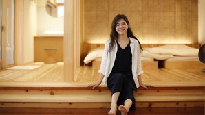 Una habitación con piso de madera, una cama con ropa blanca y un espejo en la pared.
