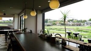 Un bar moderne doté d’un long comptoir, d’un éclairage suspendu et offrant une vue sur un paysage verdoyant grâce à de grandes fenêtres.