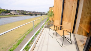 Un balcon donnant sur une rivière, une chaise et un pot de fleurs.