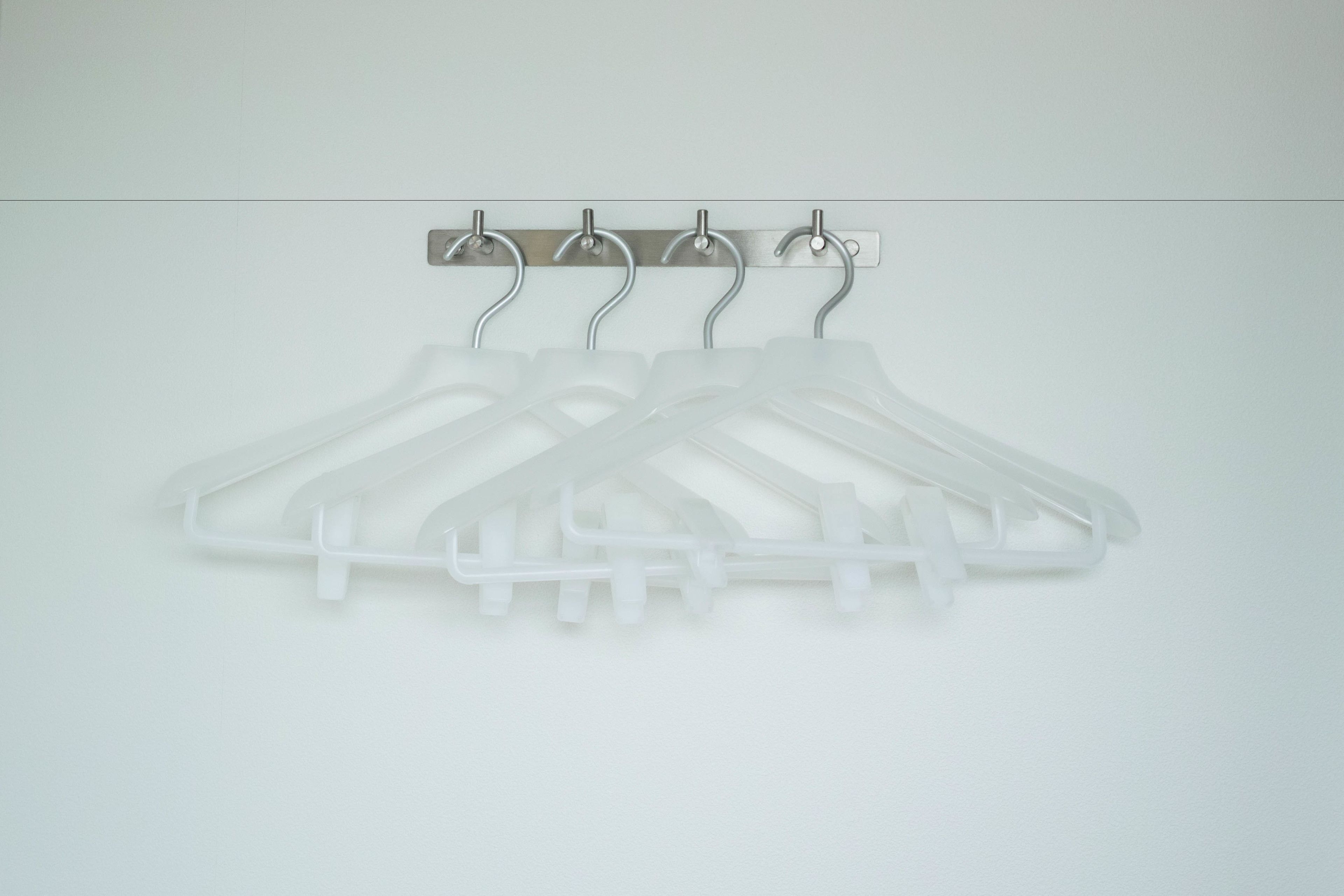 A set of white plastic coat hangers mounted on a wall.