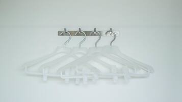 A set of white plastic coat hangers mounted on a wall.