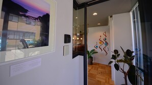 Un intérieur moderne avec une porte vitrée donnant sur un coin repas, une œuvre d’art accrochée au mur et une plante en pot.