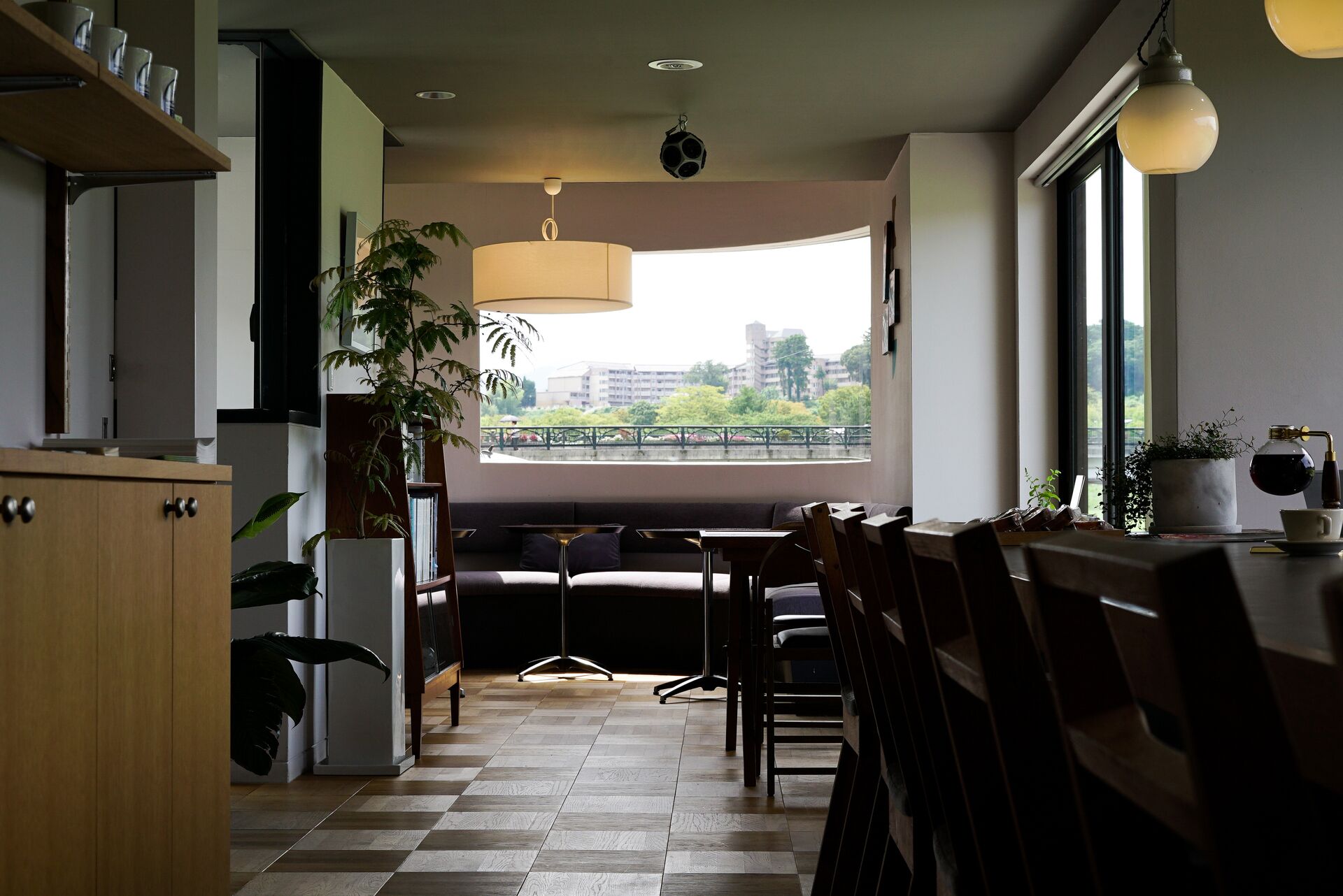 A modern kitchen with a checkered floor, wooden cabinets, and a large window offering a view of a cityscape.