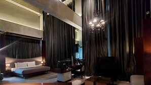 A modern living room with a large bed, a wooden coffee table, and a TV. - Kemang Icon Hotel (Jakarta)