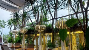 An indoor dining area with tables and chairs, surrounded by potted plants and trees. - Kemang Icon Hotel (Jakarta)