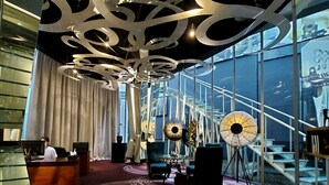 A hotel lobby with a reception desk, seating area, and a staircase leading to upper floors. - Kemang Icon Hotel (Jakarta)