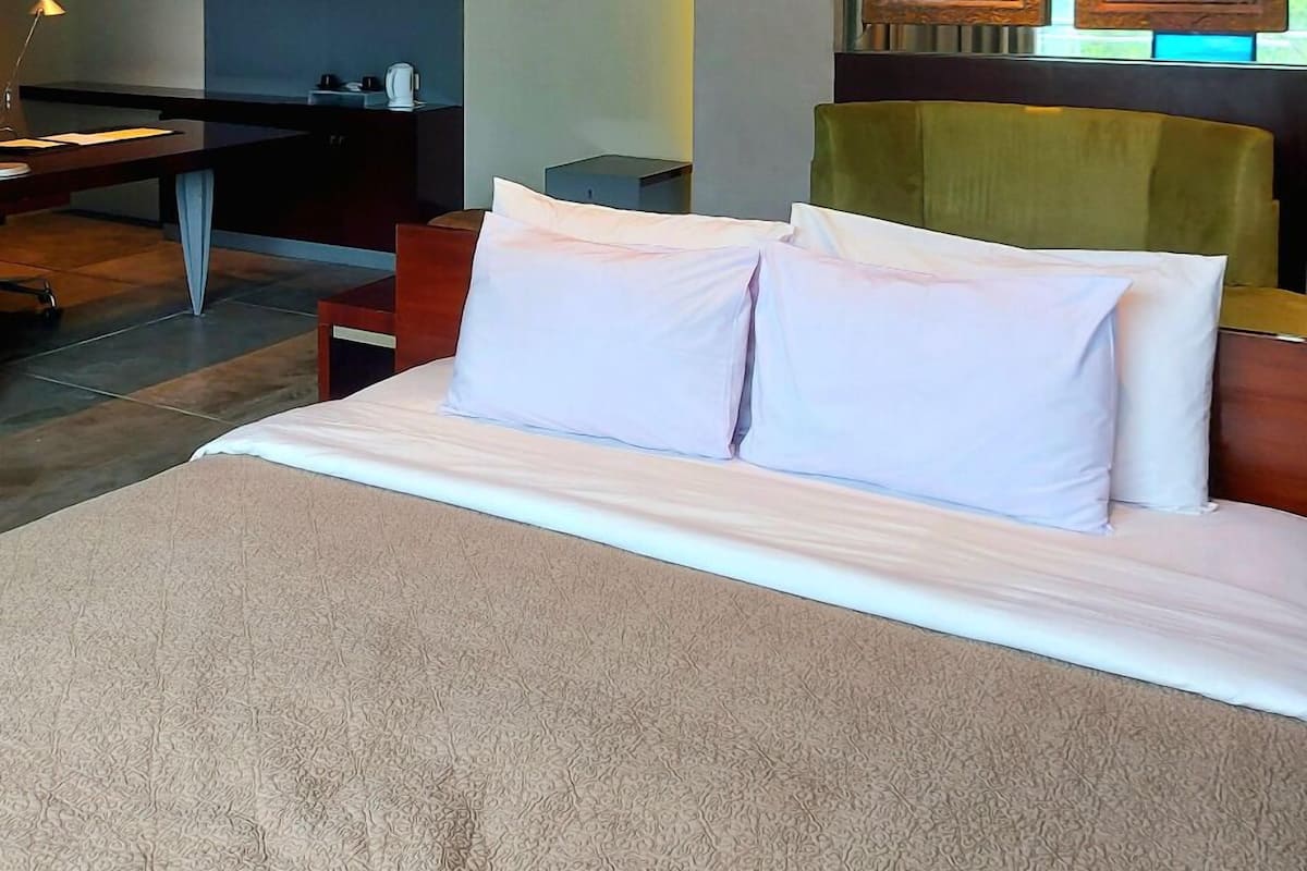 A modern hotel room with a large bed, a desk, a chair, and a television.