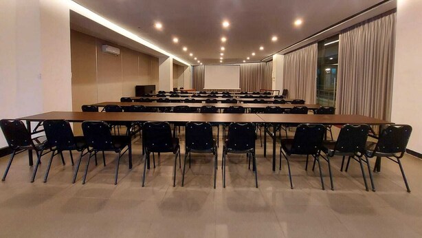 A conference room with a long table and chairs, recessed ceiling lights, and large windows with curtains. - Kemang Icon Hotel (Jakarta)