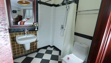 A bathroom with a checkered floor, a sink, a shower, and a toilet.