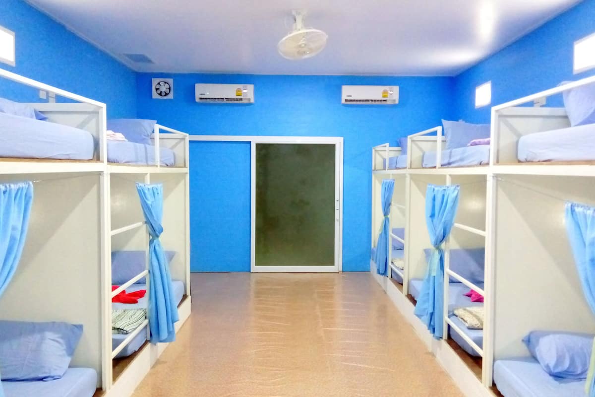A room with bunk beds, blue curtains, and air conditioning units on the walls.