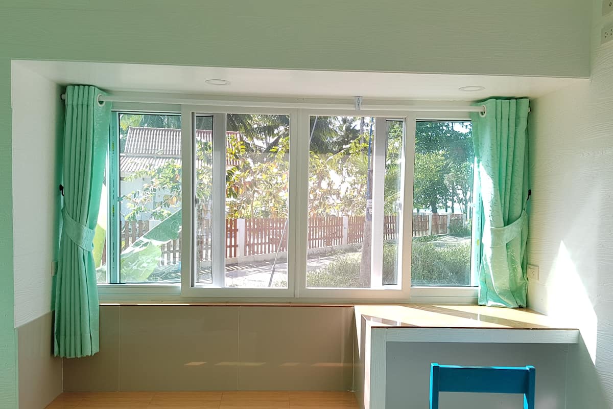 A room with a large window, a wooden bench, and a blue chair.