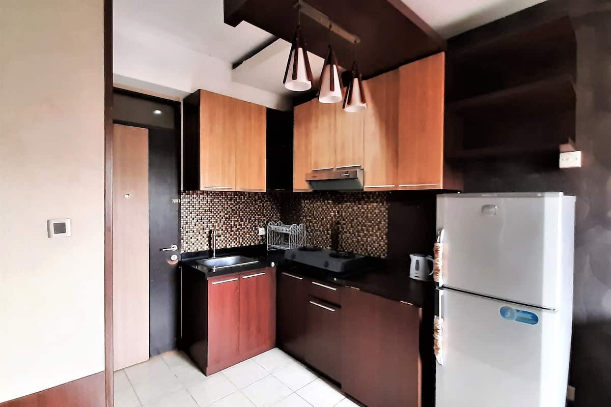 Una cocina moderna con armarios de madera, encimera negra, refrigerador de acero inoxidable y salpicadero de azulejos.