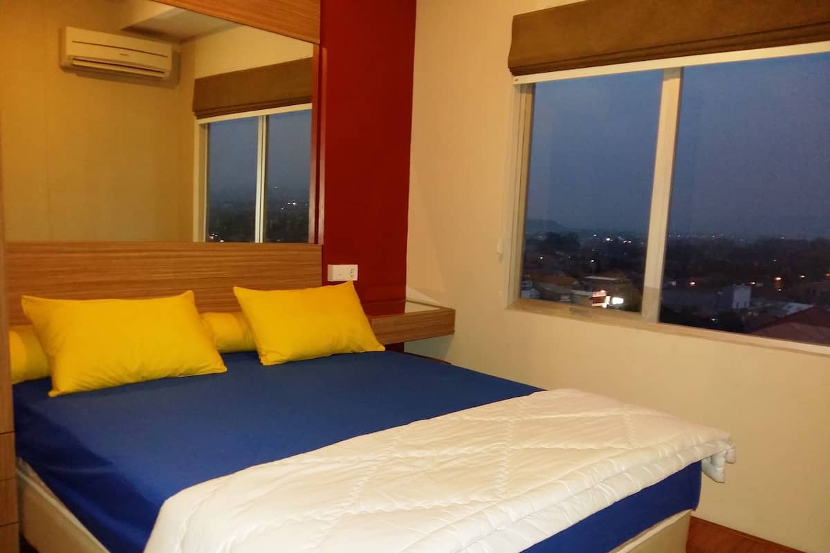 Un dormitorio con cama, ventana y aire acondicionado.