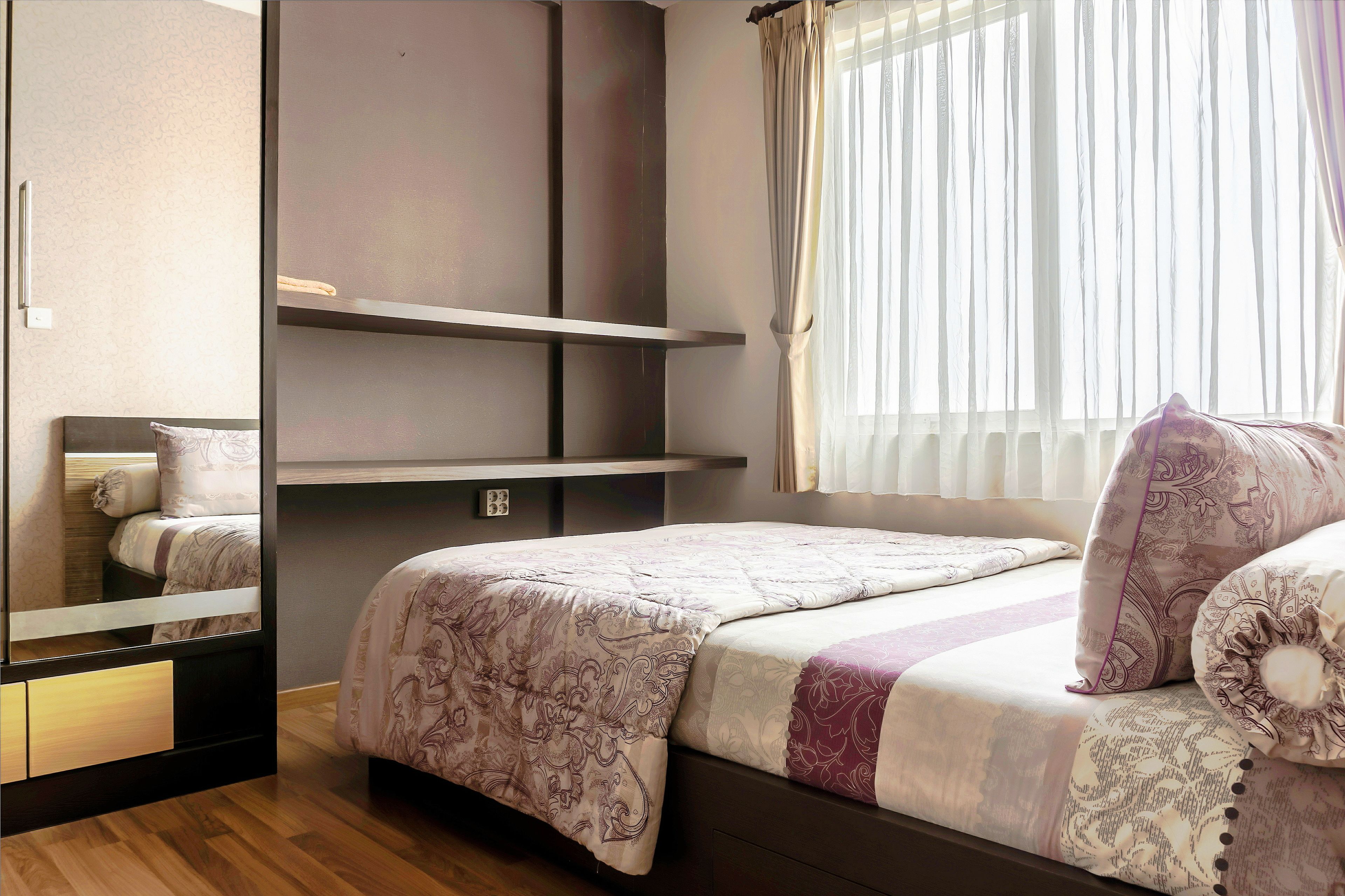 A bedroom with a bed, a wardrobe, and a window with curtains.