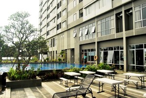 Un edificio moderno con piscina, area relax all'aperto e un albero.