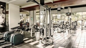A gym with various exercise equipment, large windows, and a checkered floor. - High Livin Apartment Baros (Cimahi)