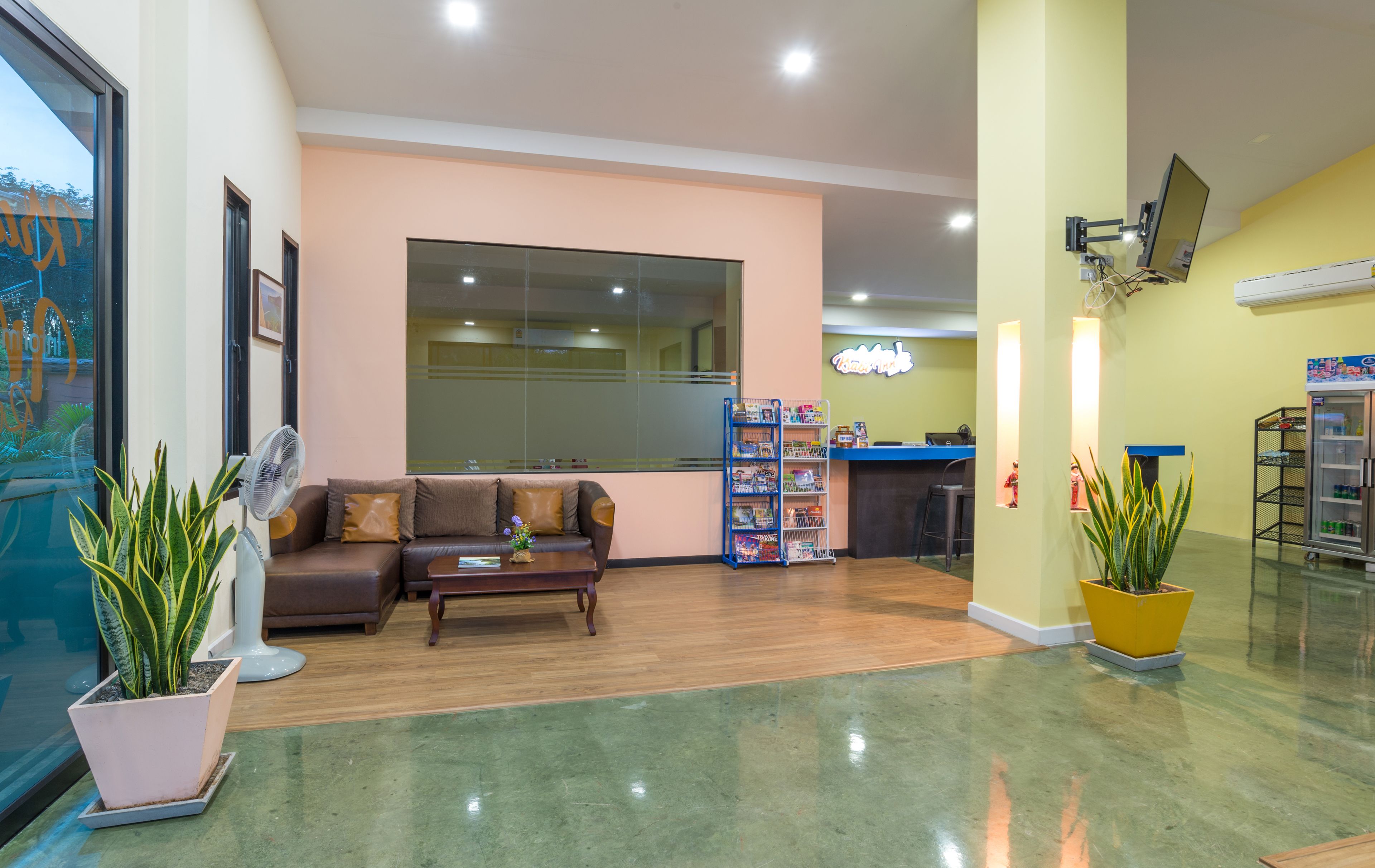 A spacious lobby with a reception desk, a seating area with a sofa and coffee table, and a large window.