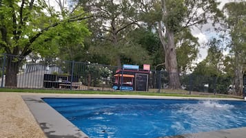 Una piscina al aire libre de temporada, sombrillas