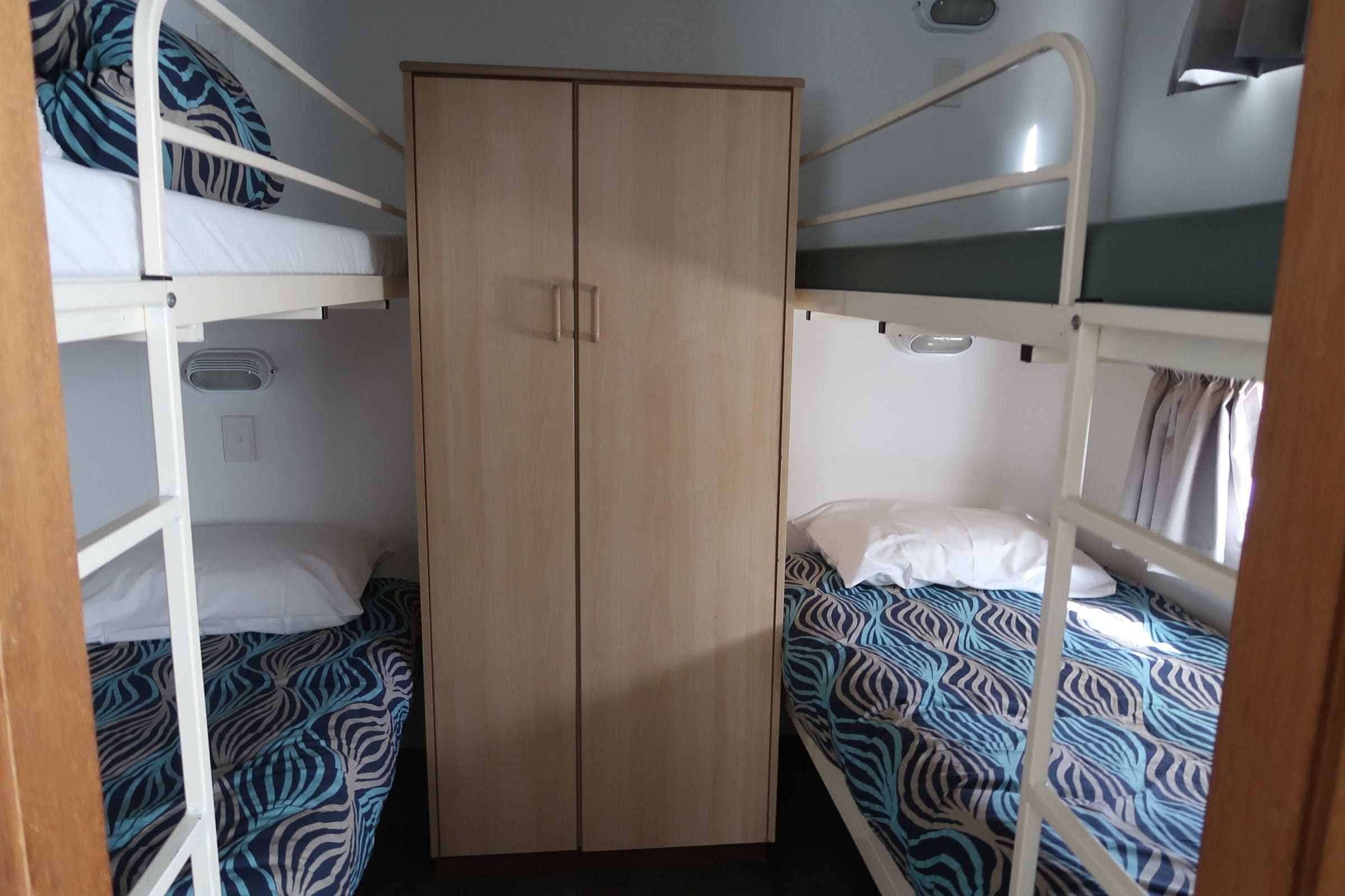 Quarto com beliche, guarda-roupa e janela.