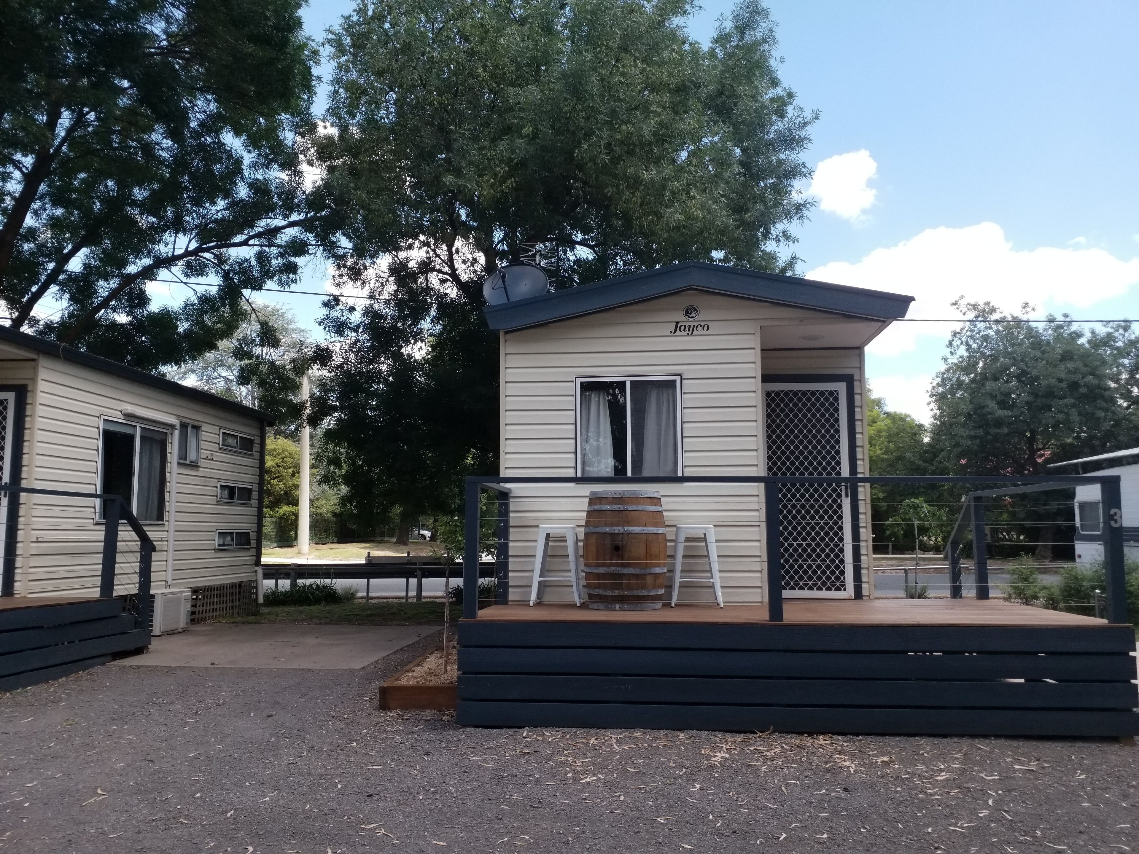 Une petite maison mobile de plain-pied, dotée d’un porche et d’un tonneau.