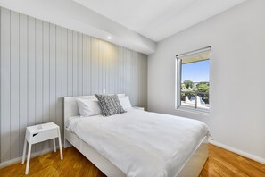 A modern bedroom with a bed, bedside table, and a window with a view.
