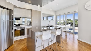 A modern kitchen with a large island, stainless steel appliances, and a view of the outdoors. - Robe Marina Accommodation (Robe)