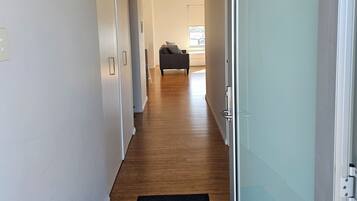 A hallway with a wooden floor, a black doormat, and a door labeled "4 Marina".