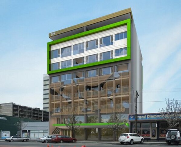 A modern multi-story building with a green and white facade, large windows, and a visible storefront at the ground level. - Exodus Dandenong Apartment Hotel (Melbourne)