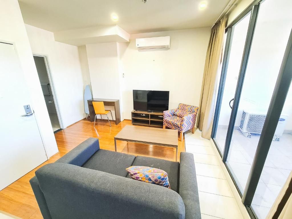 A modern living room with a sofa, a coffee table, a TV, and a patterned chair.