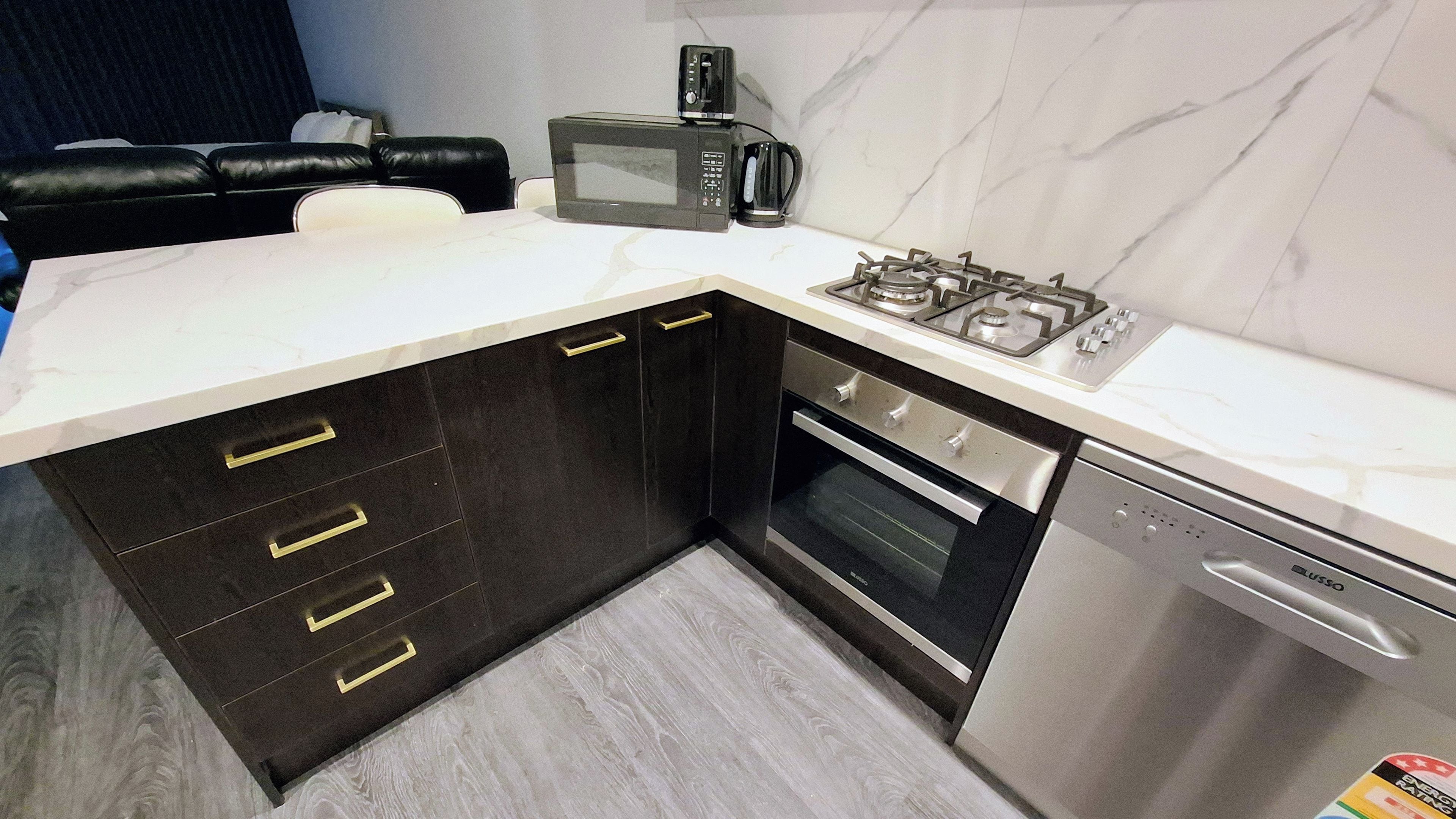 A modern kitchen with dark cabinets, a microwave, a gas stove, an oven, and a dishwasher.