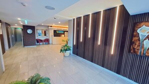 A hotel lobby with a reception desk, seating area, and a large wall with vertical lines. - Exodus Dandenong Apartment Hotel (Melbourne)