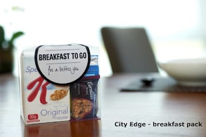 Un plateau de petit-déjeuner sur une table, accompagné d’une pancarte indiquant : « Petit-déjeuner à emporter pour prendre soin de vous. »