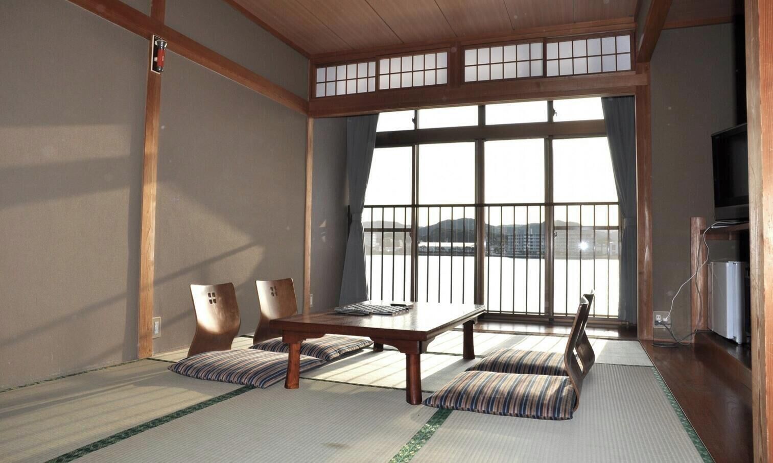 A traditional Japanese room with tatami flooring, a low table, and chairs.
