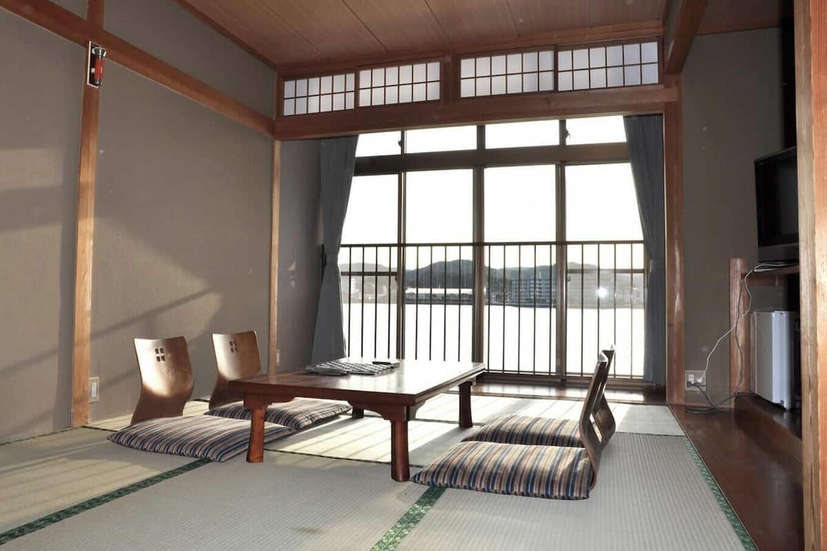 Perinteinen japanilainen huone, jossa on tatamimatto, matala pöytä ja tuolit.