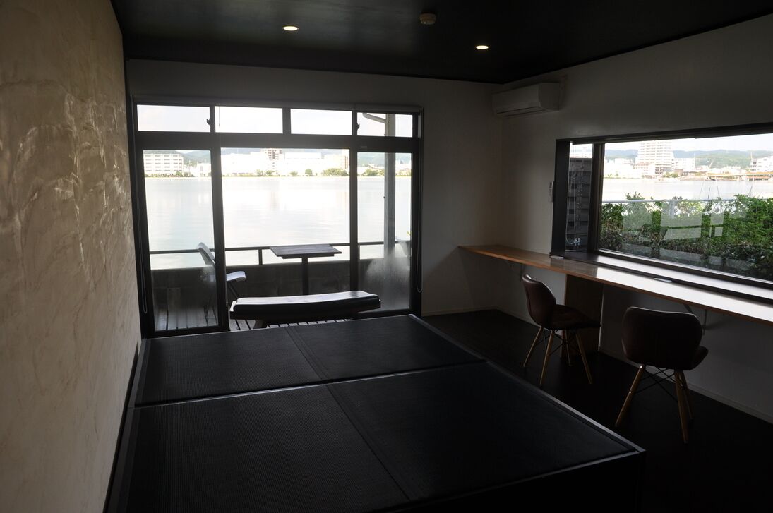 Quarto com uma janela grande, uma mesa e duas cadeiras.