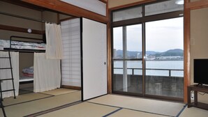 A room with tatami flooring, a bunk bed, a sliding door, and a view of a body of water and distant mountains. - Kahan no Yado Karatsu Castle (Karatsu)
