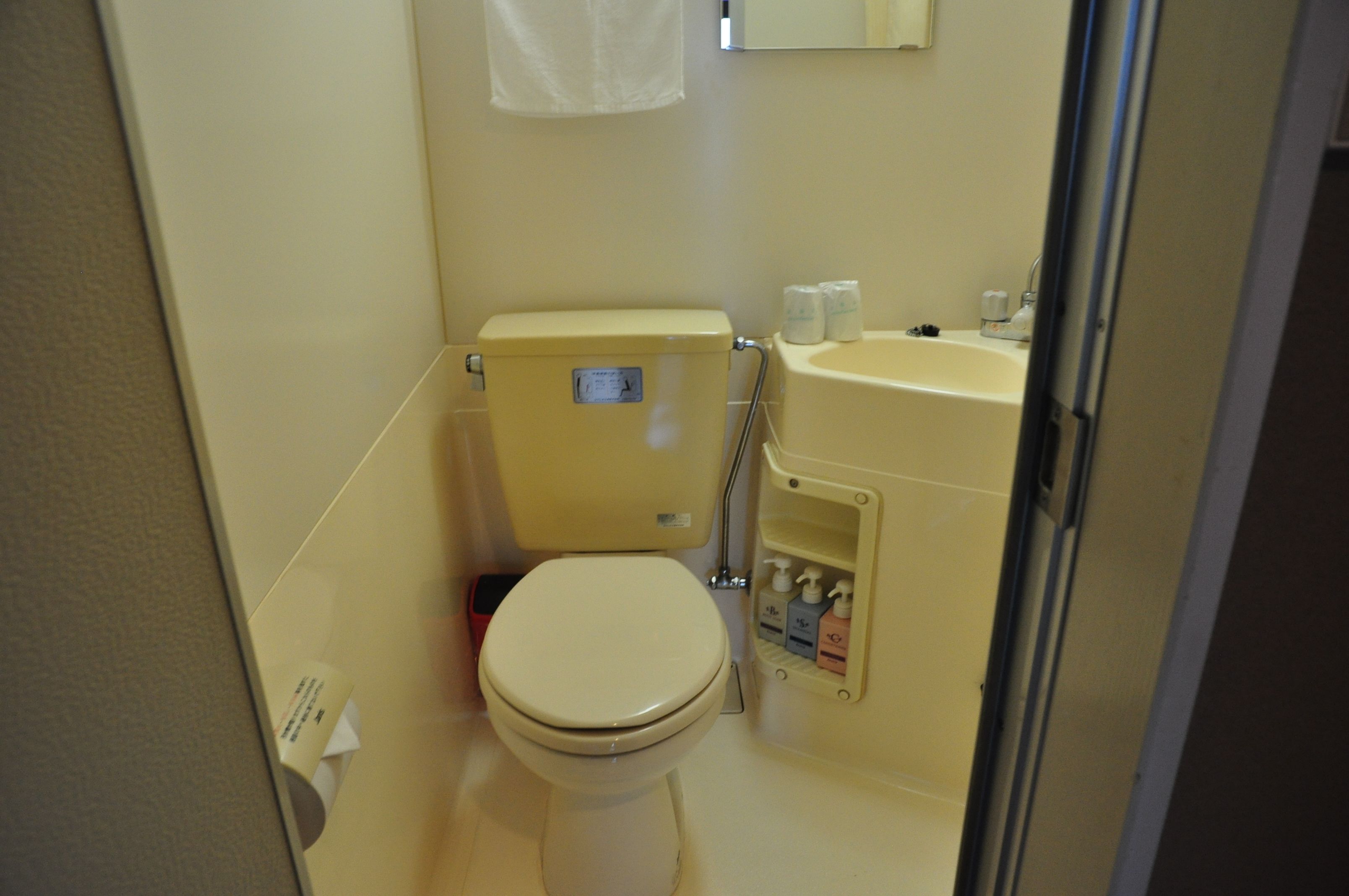 Un baño pequeño con inodoro, lavamanos y espejo.