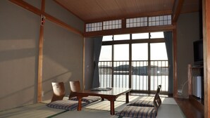 A traditional Japanese room with tatami flooring, a low table, cushions, and a view of the sea through large windows. - Kahan no Yado Karatsu Castle (Karatsu)