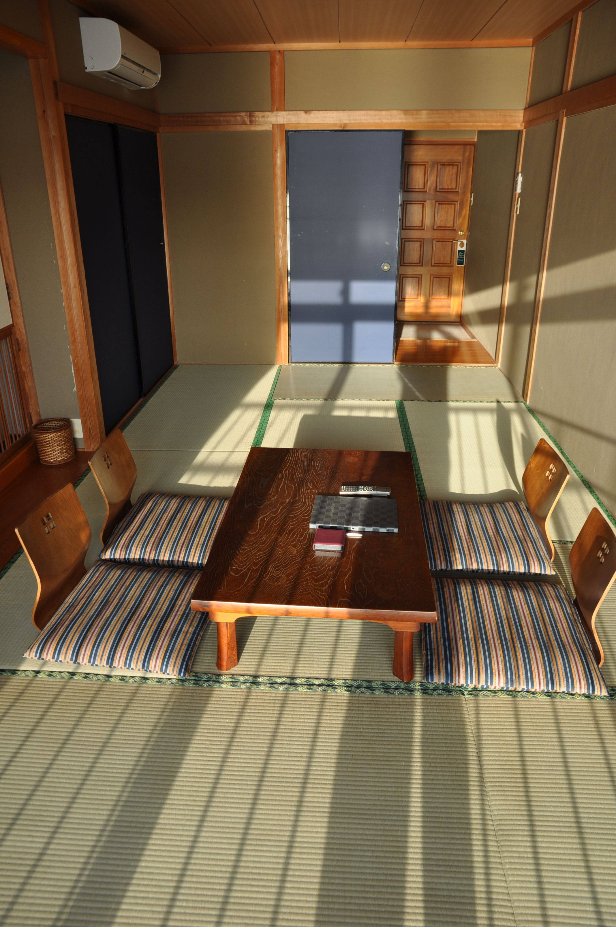 A tatami mat room with a wooden table, chairs, and a sliding door.