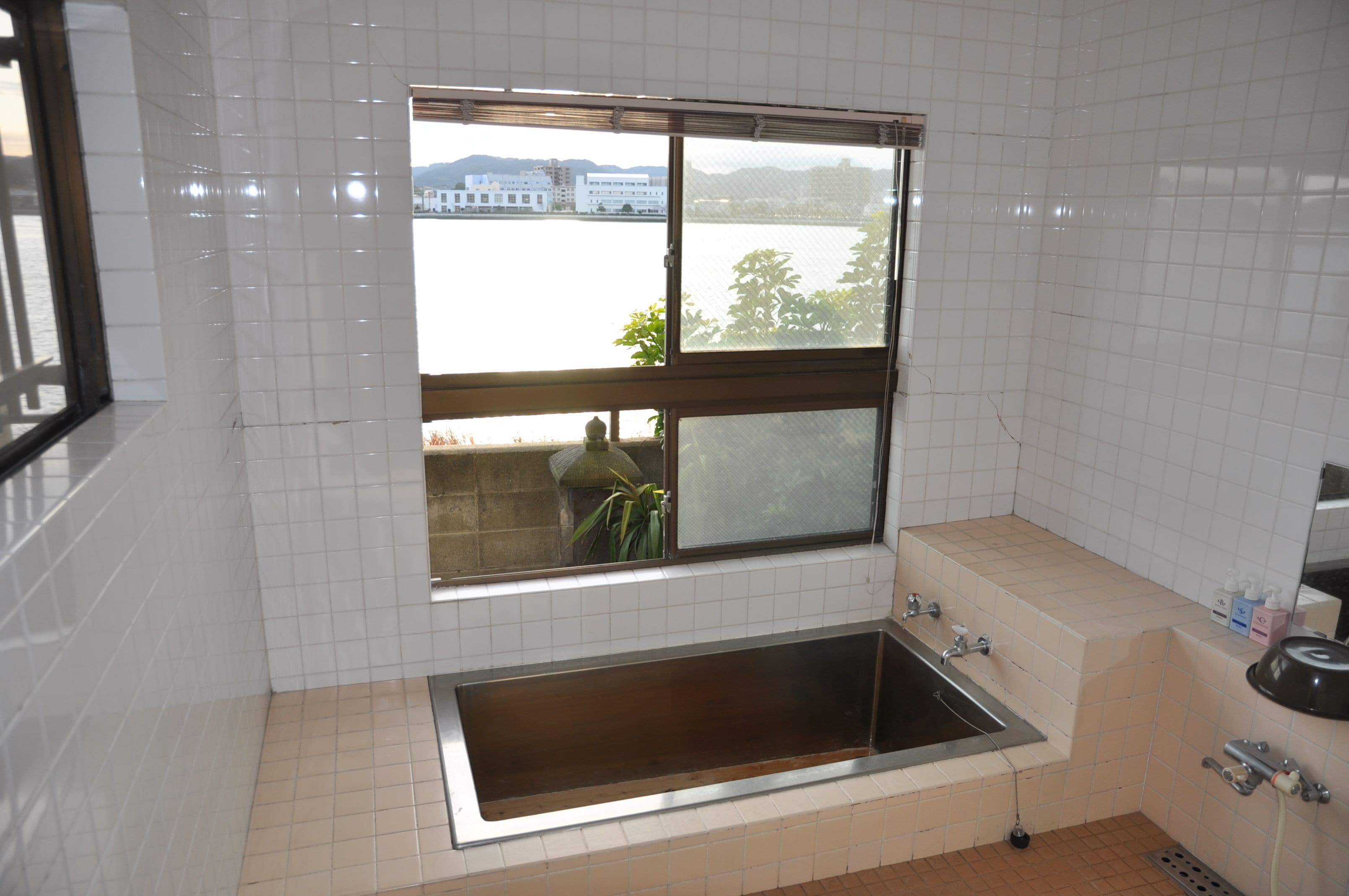 Een badkamer met een raam, een wastafel en een spiegel.