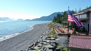 A beach with a wooden deck, an American flag, and a mountain backdrop.