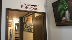 A hallway with a sign reading "Fuku tomi" and a painting of a tree with a glass on the wall. - Women's Guest House Fukutomi (Naha)